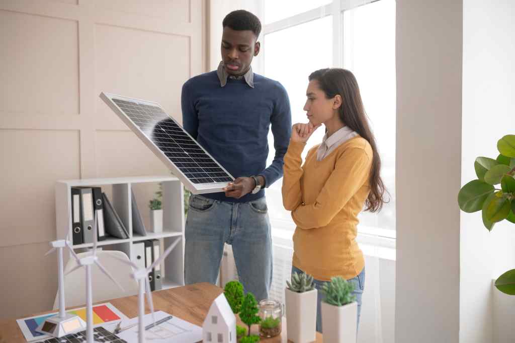 A man standing with a woman holding a solar panel in his hand