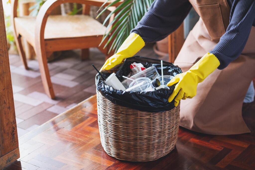 A woman cleaning and taking garbage bag out of the trash bin at home